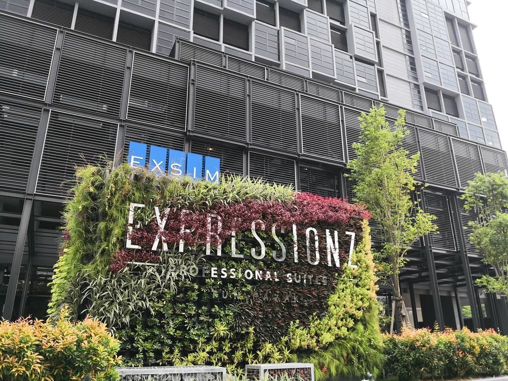 A building with a sign for 'EXPRESSIONZ PROFESSIONAL SUITES' surrounded by lush greenery.