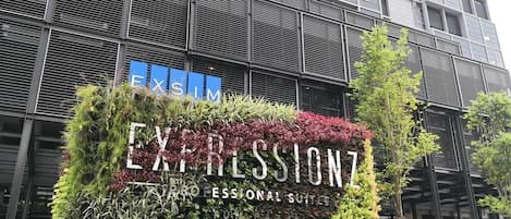 Un immeuble portant une enseigne indiquant « EXPRESSIONZ PROFESSIONAL SUITES », entouré d’une végétation luxuriante.