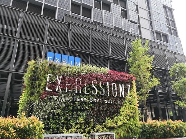 A building with a sign for 'EXPRESSIONZ PROFESSIONAL SUITES' surrounded by lush greenery.