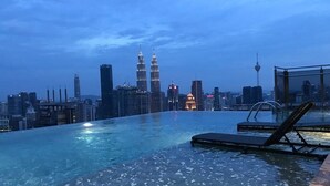 Una piscina infinita con vistas al horizonte urbano, incluyendo edificios destacados.
