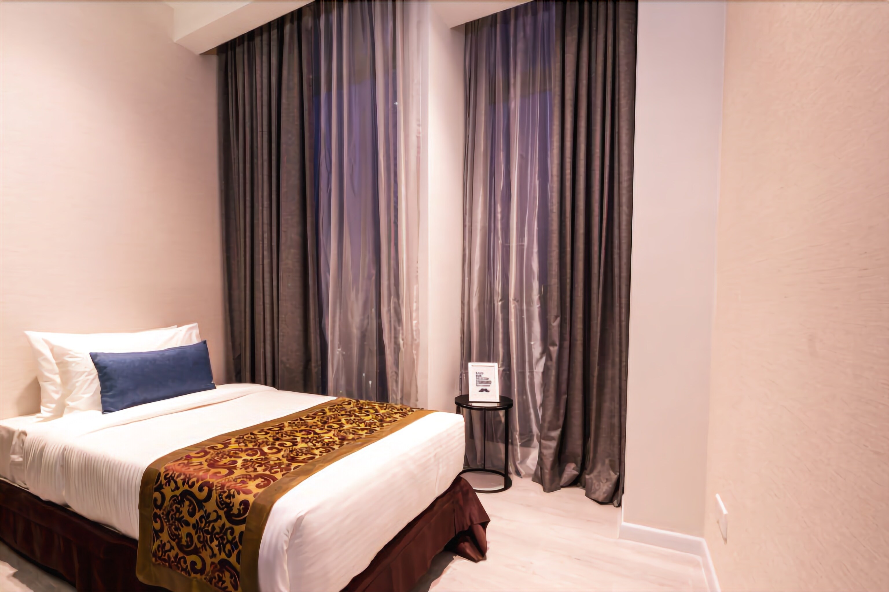 Ein Hotelzimmer mit einem großen Bett, einem Nachttisch und einem Vorhang im Hintergrund.