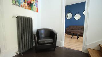 A room with a radiator, a black leather chair, and a blue wall with three round mirrors.