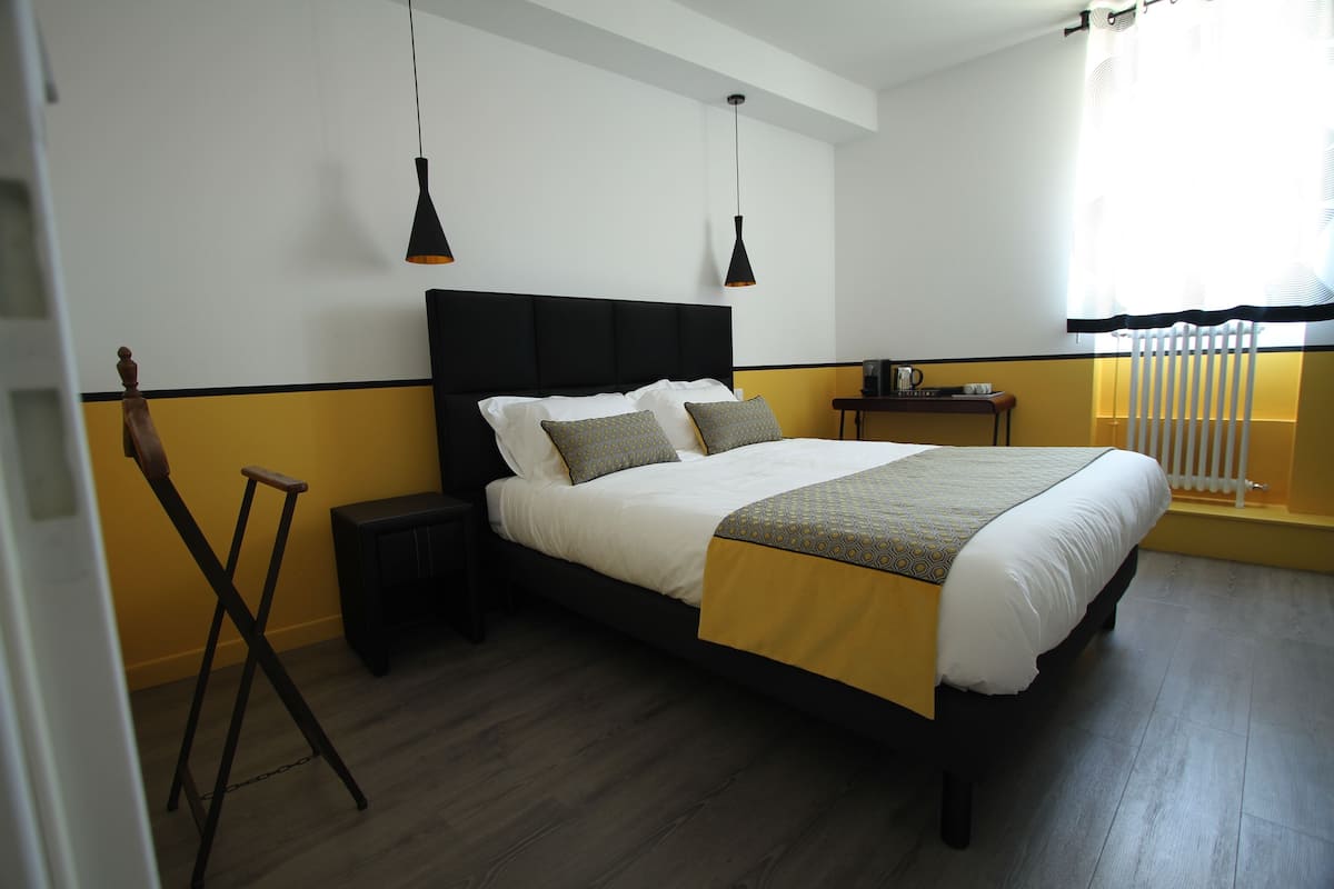 A neatly arranged bedroom with a large bed, bedside tables, and hanging pendant lights.