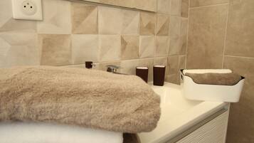 A bathroom with a sink, mirror, towel rack, and a trash bin.