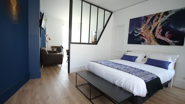 Un dormitorio con cama, banco y un cuadro en la pared.