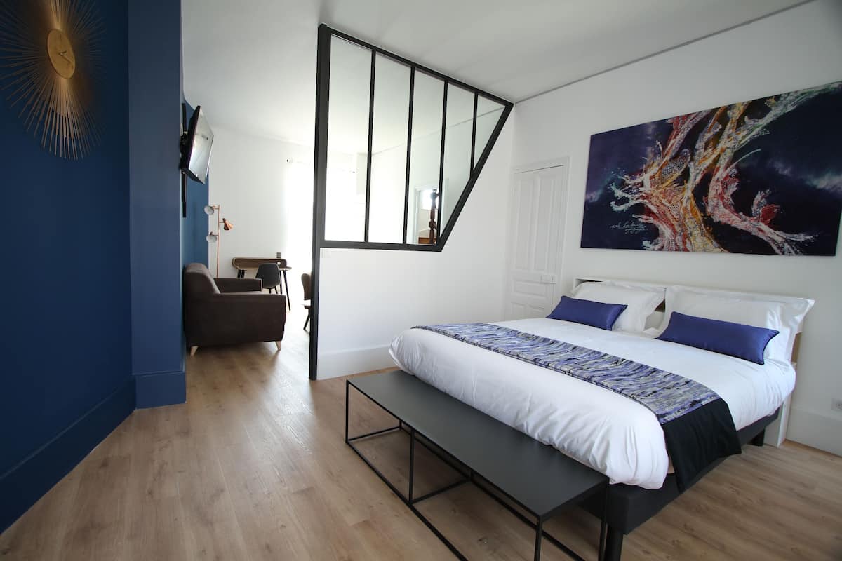 A bedroom with a bed, bench, and a painting on the wall.
