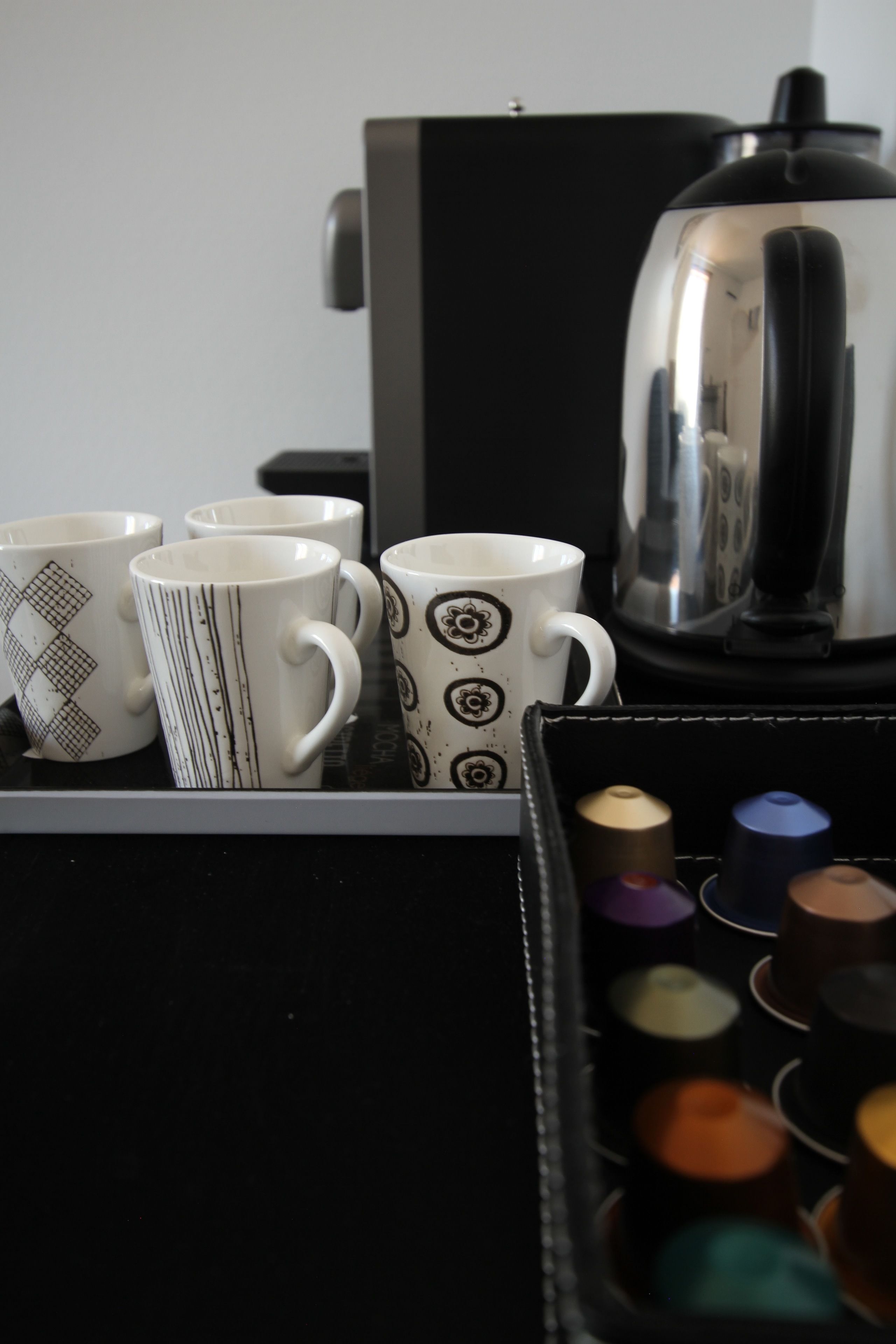 A coffee machine and a tray with mugs and coffee capsules.