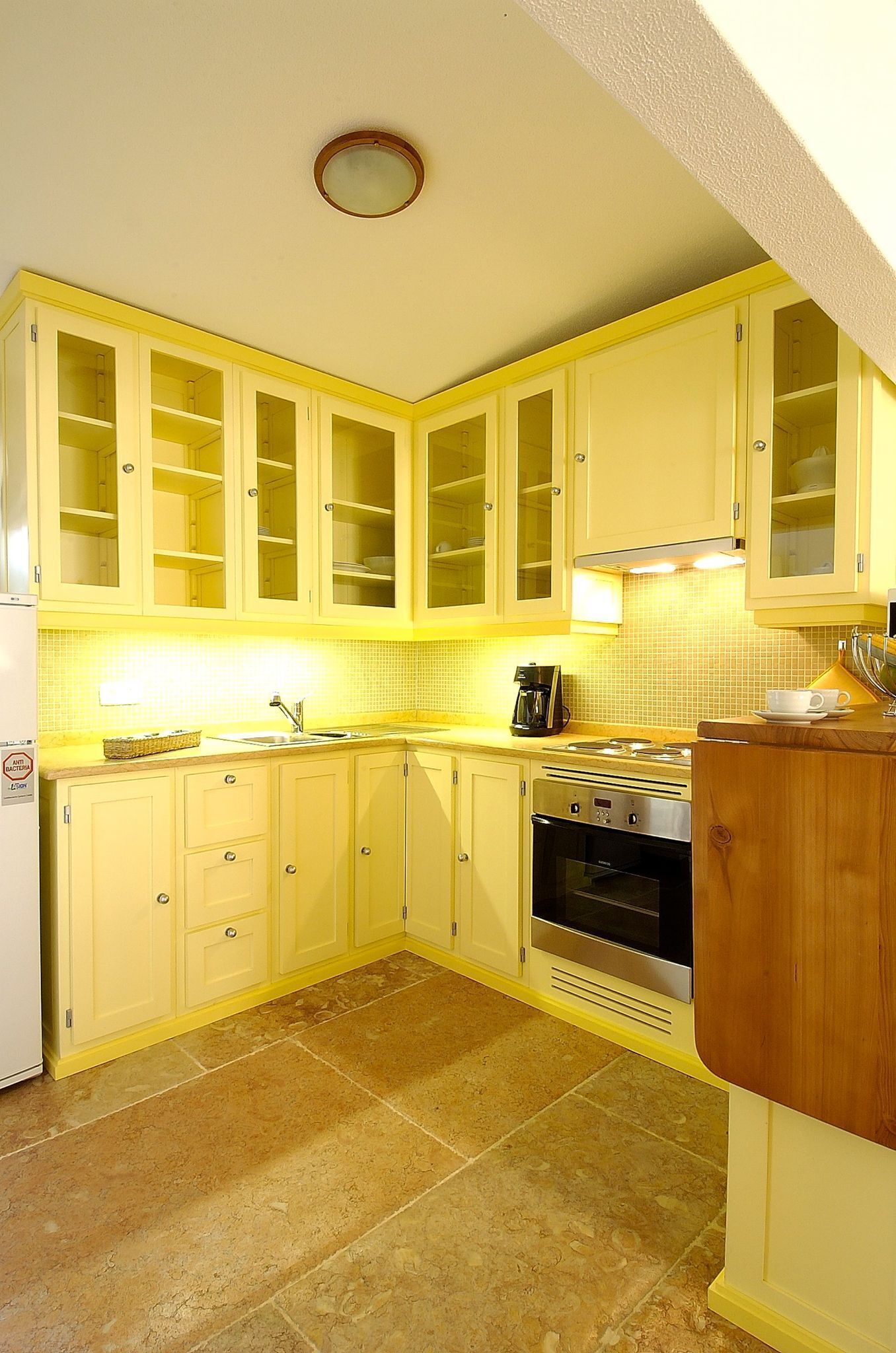 A compact kitchen with yellow cabinets, a stove, and a sink.
