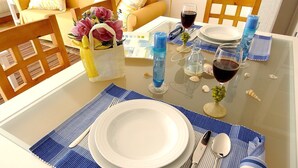 A dining table set with plates, cutlery, and glasses, accompanied by a woven basket with flowers and a bottle of water.