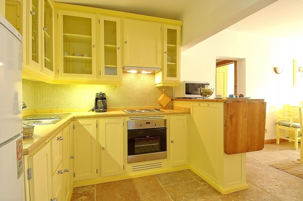 A compact kitchen with yellow cabinets, a built-in oven, and a microwave.