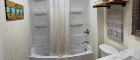 A bathroom with a bathtub, toilet, and sink.