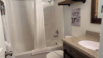 A bathroom with a bathtub, toilet, and sink.