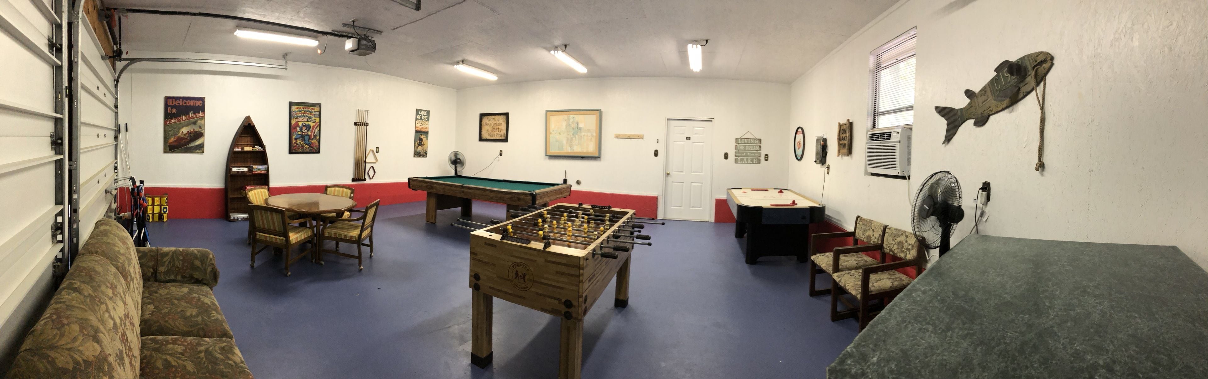 Een kamer met een pooltafel, tafelvoetbal en een bank.