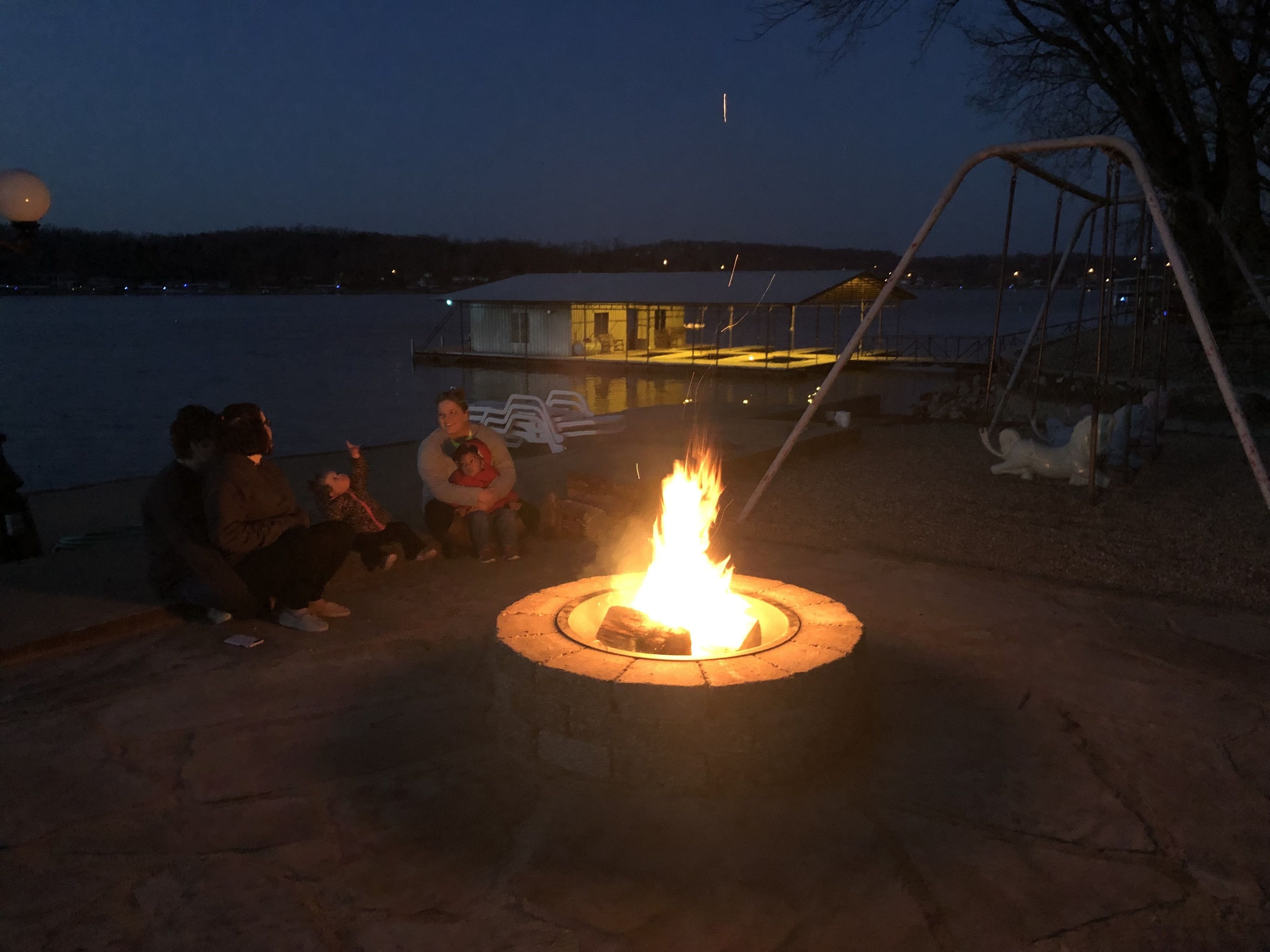 A group of people sitting by a campfire at night.