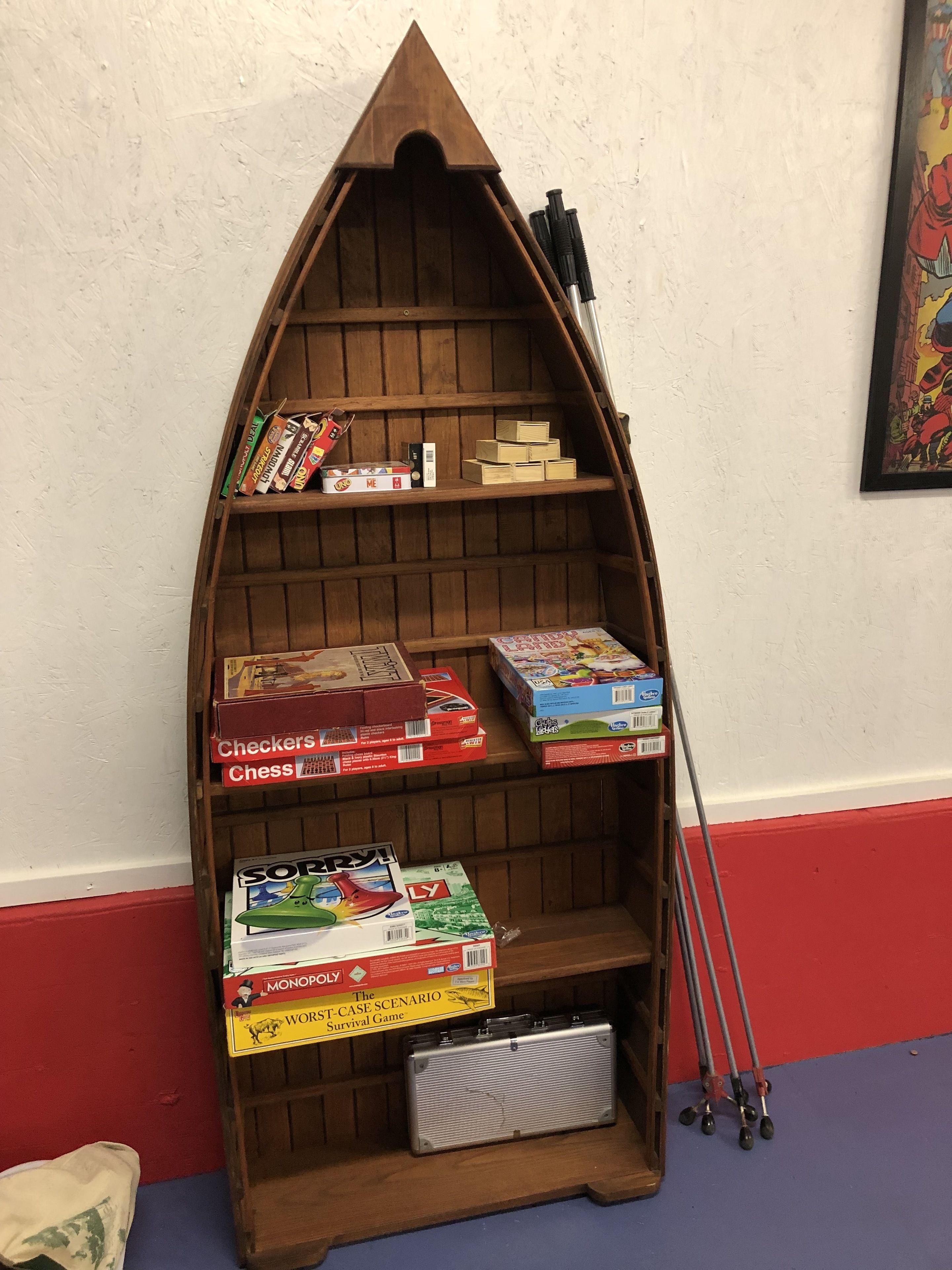A wooden boat-shaped bookshelf with various board games and a vintage radio.