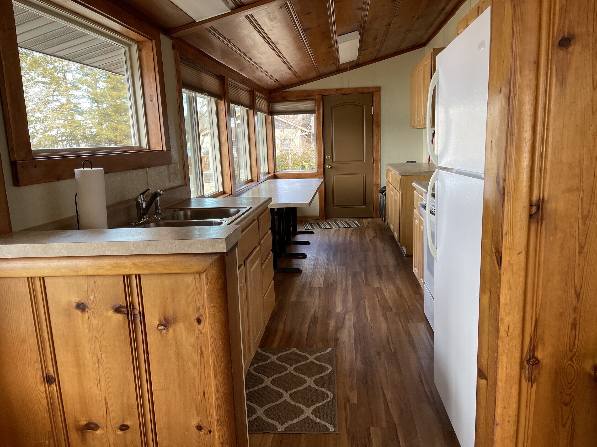 A kitchen with wooden cabinets, a sink, and a refrigerator.
