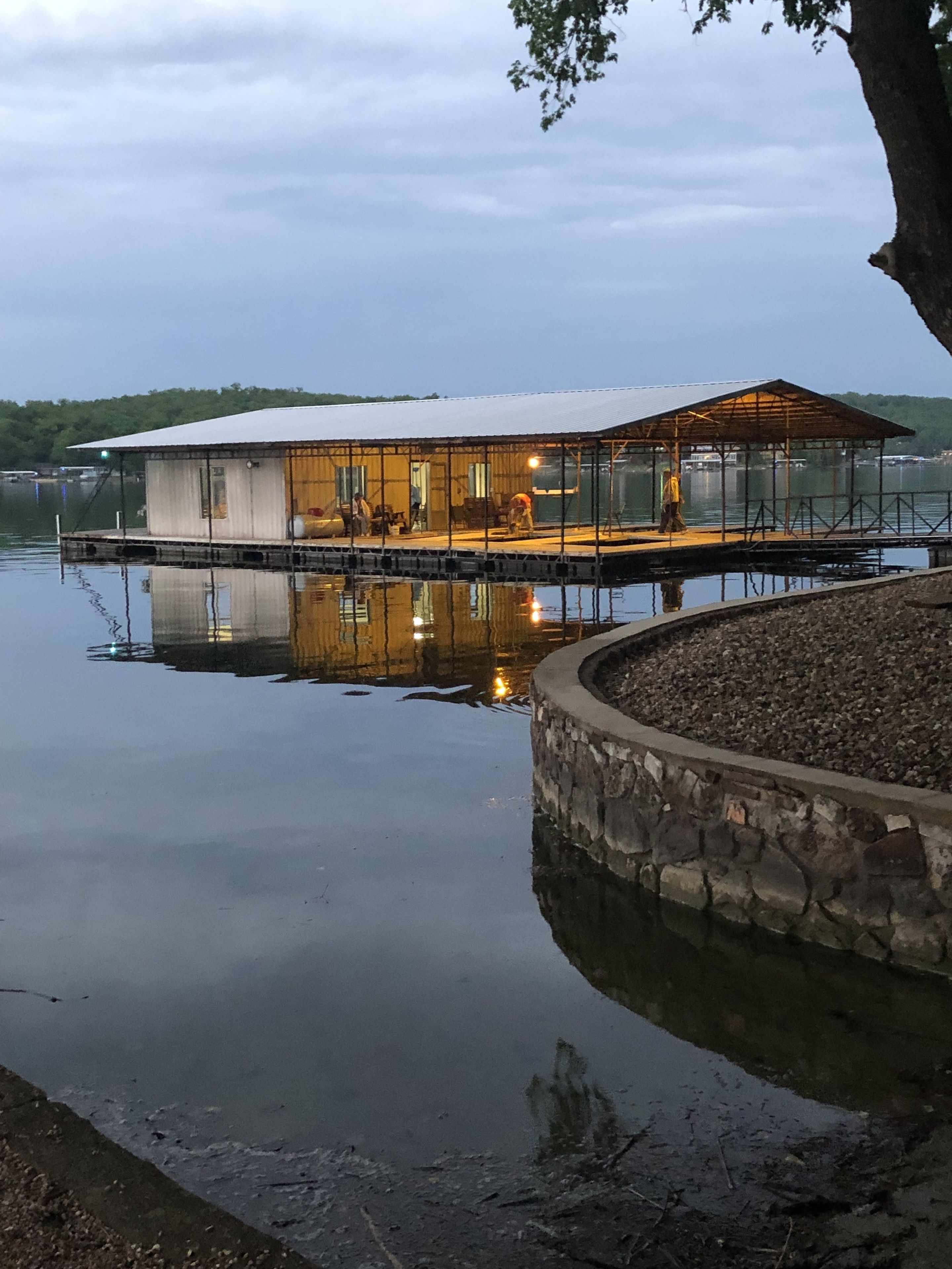 A floating house with a covered deck and a stone retaining wall.