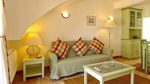 A cozy living room with a sofa, two lamps, a glass coffee table, and a cabinet. - Giddah Green Apartment, Pool, Wifi, AC (Olhos de Água)