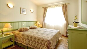 A hotel room with a bed, nightstands, a lamp, a dresser, a mirror, and a window with curtains. - Giddah Green Apartment, Pool, Wifi, AC (Olhos de Água)