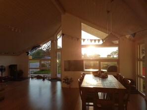 Ein geräumiges Zimmer mit großem Esstisch, Deckenventilator und Blick ins Freie.