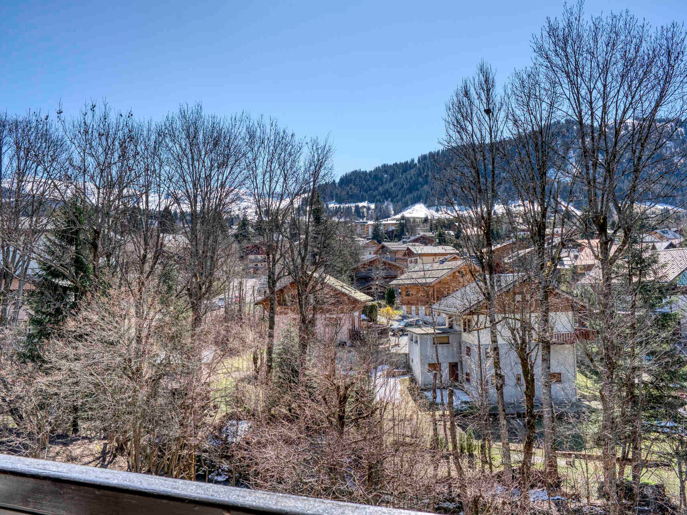 Un quartier résidentiel avec des maisons et des arbres, un ciel dégagé et une chaîne de montagnes à l’horizon.