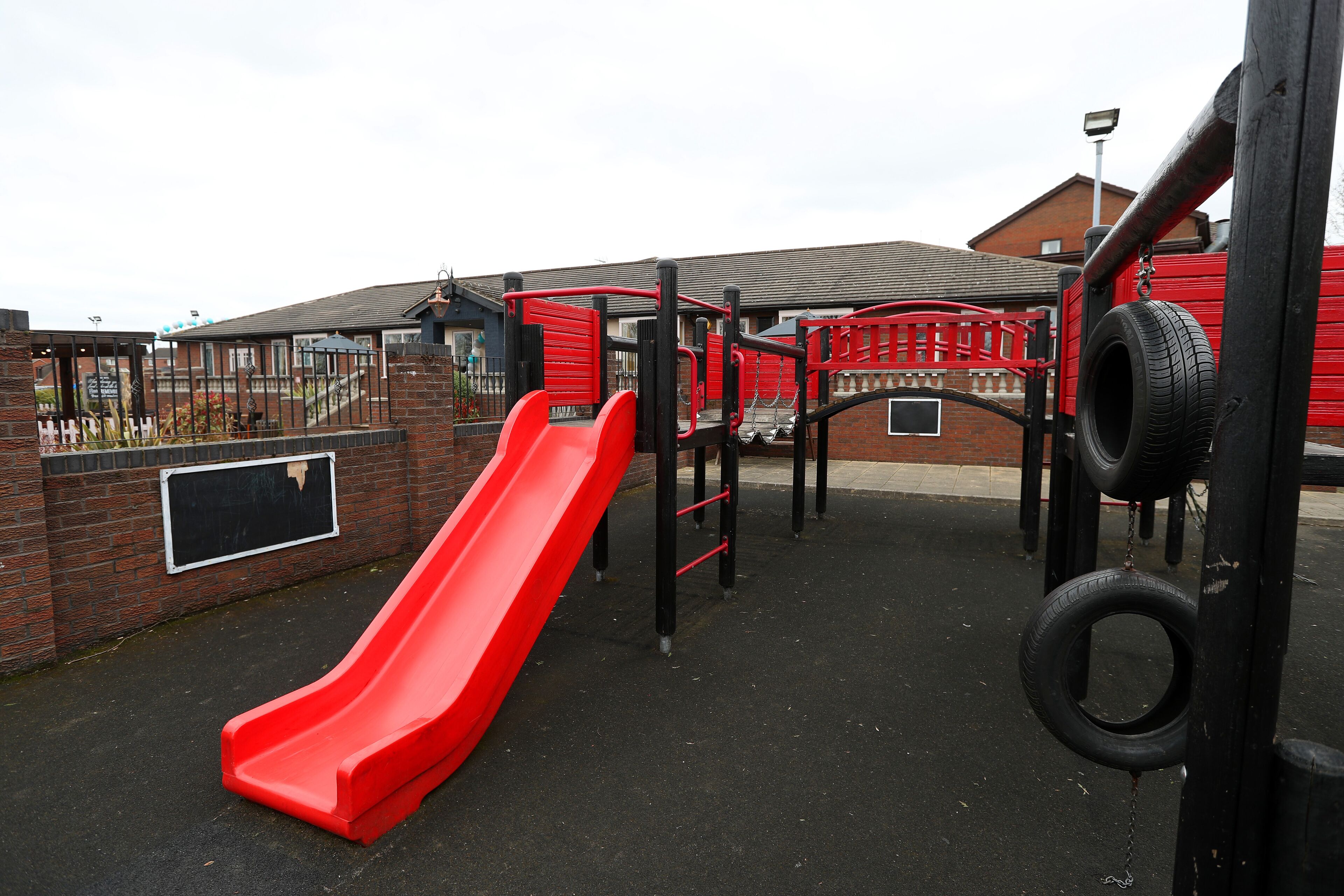 A playground with a red slide and climbing structures.
