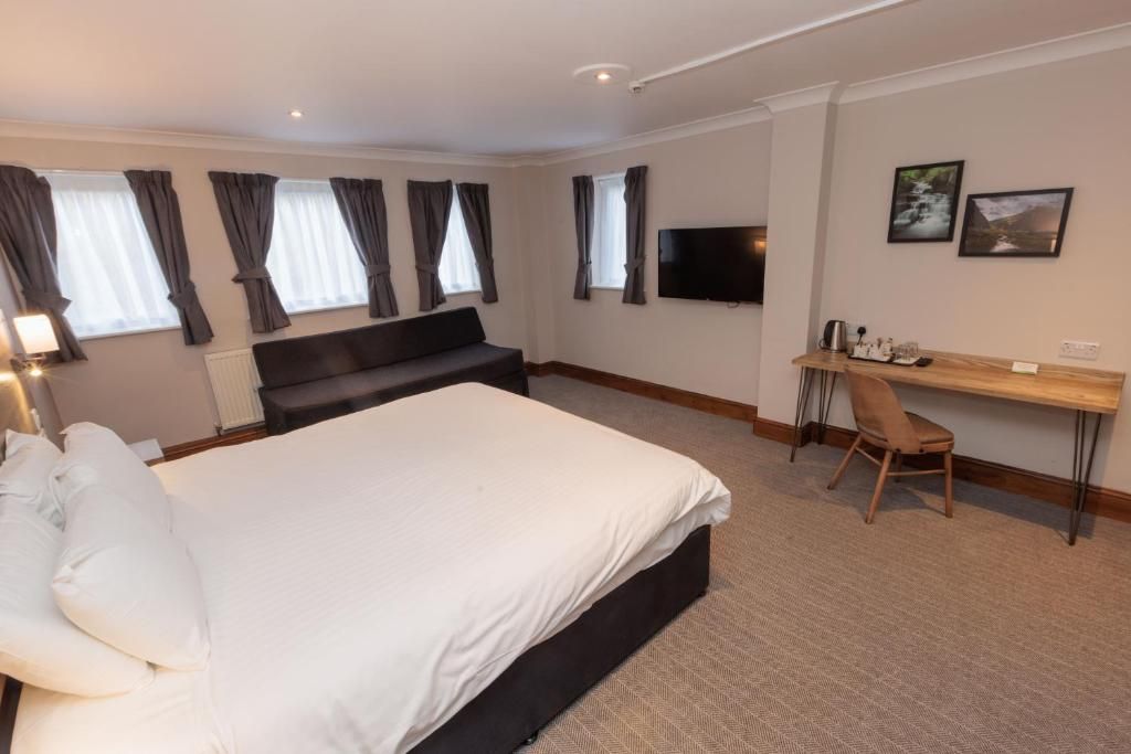 A hotel room with a bed, a desk, a chair, a TV, and curtains.