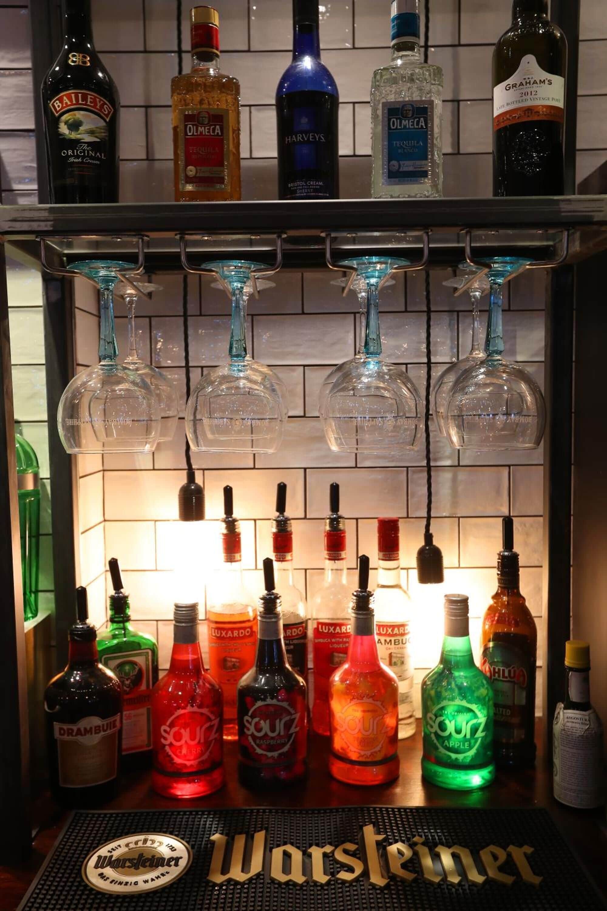 Zona de bar con varias botellas de licores y vasos.