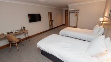 A hotel room with two beds, a desk with a chair, a television, and a mirror.