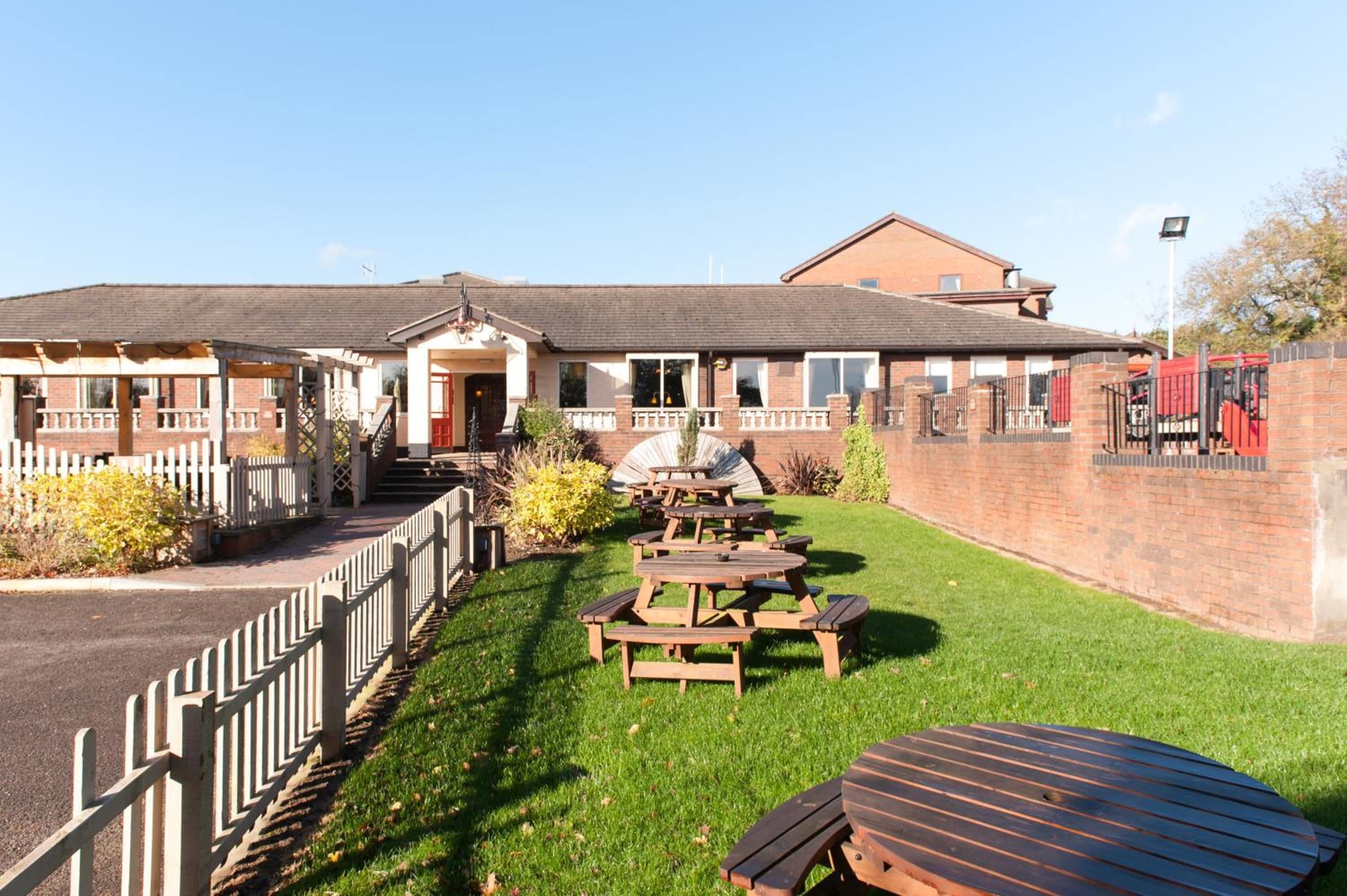 A building with a covered patio area, outdoor seating, and a brick wall.