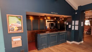 A hotel reception area with a wooden counter, a sign for a breakfast menu, and a reception desk. - Boundary, Alfreton by Marston's Inns (Alfreton)