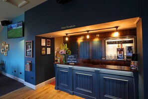 A hotel reception area with a bar, a television displaying a sports event, and framed certificates on the wall. - Boundary, Alfreton by Marston's Inns (Alfreton)
