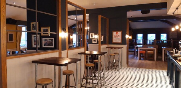 A bar area with stools, a counter, and framed pictures on the wall.