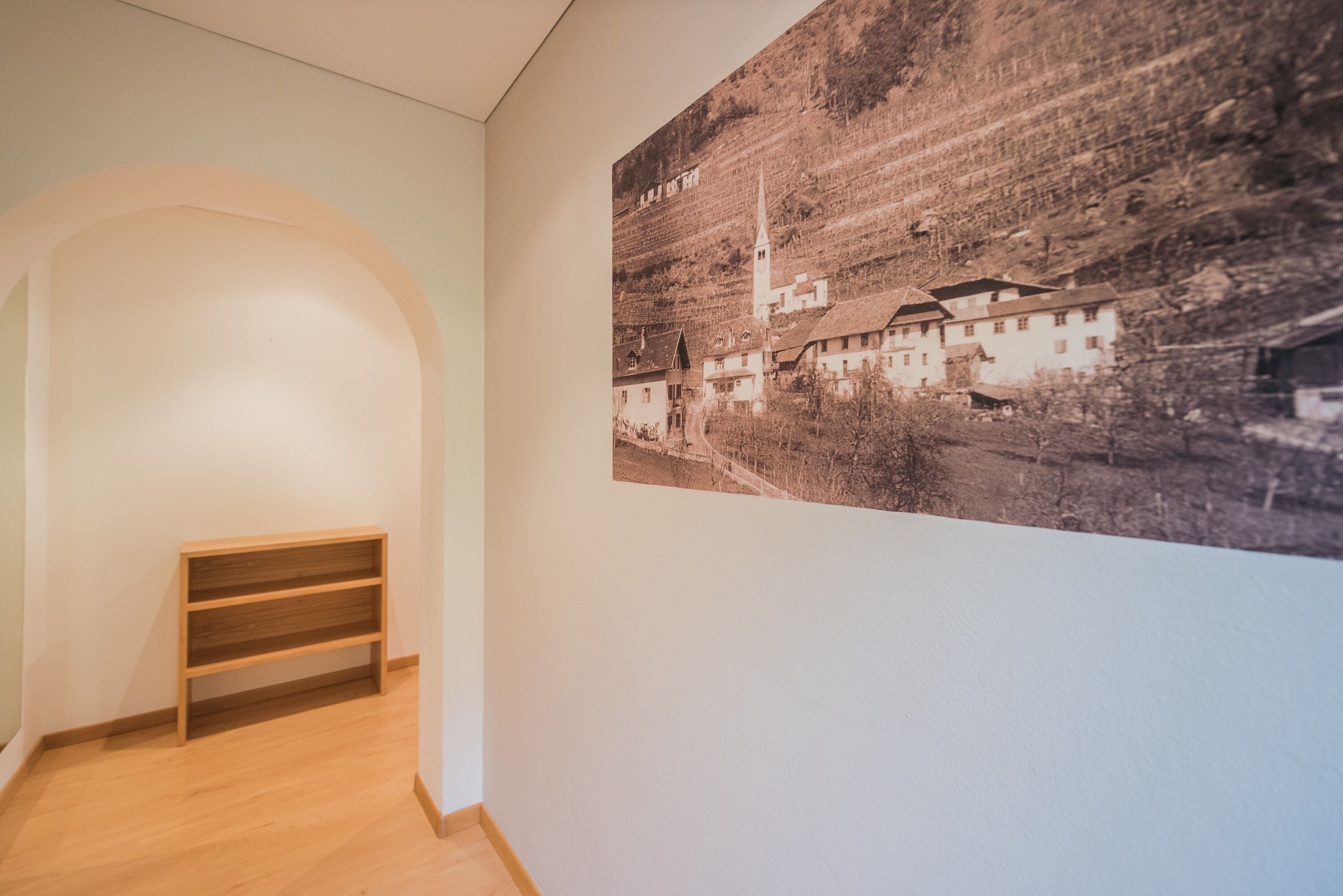 A hallway with a wooden bench and a large black and white photograph on the wall.