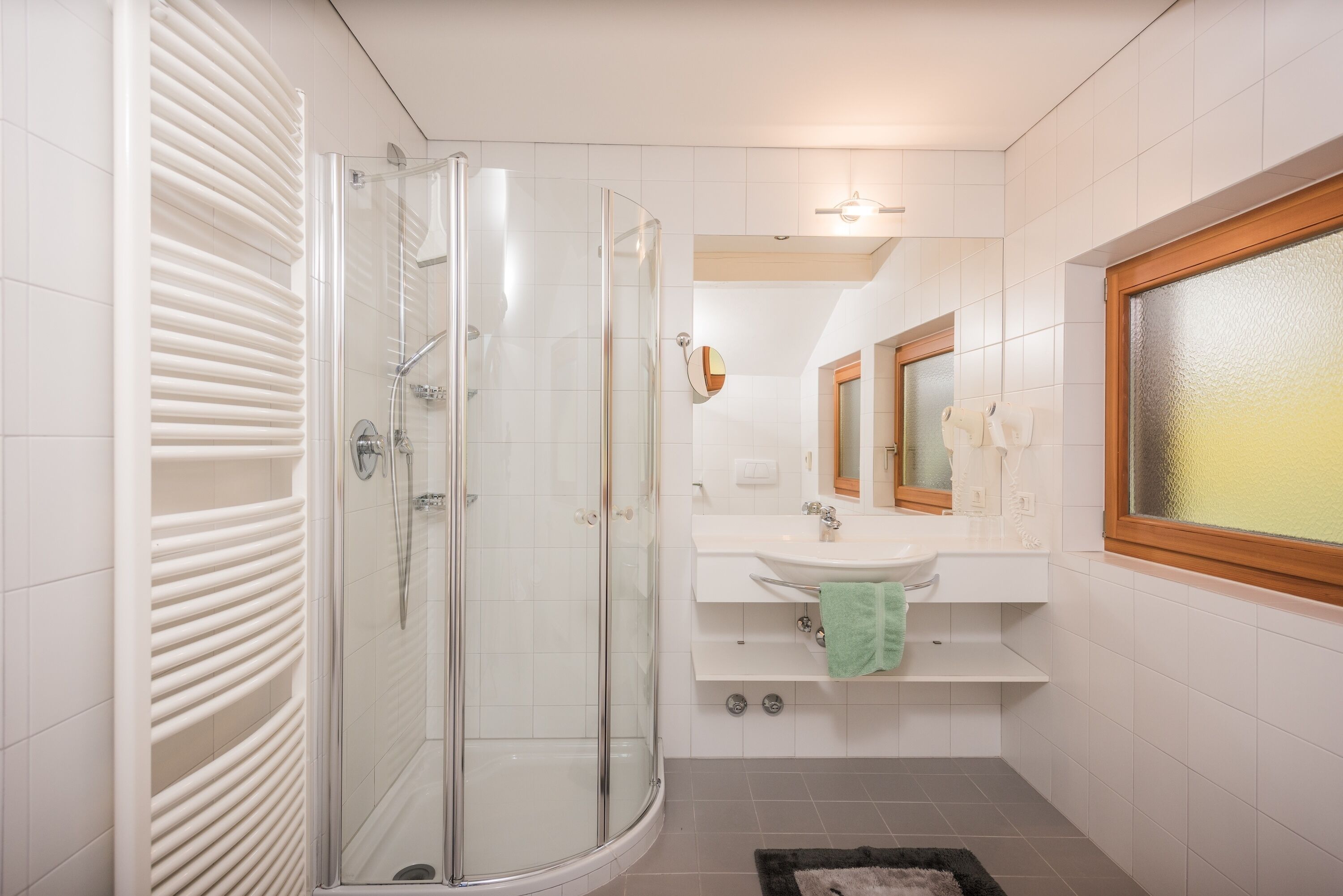 A modern bathroom with a glass-enclosed shower, a white sink, and a mirror above it.