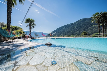Una piscina al aire libre, sillones reclinables de piscina