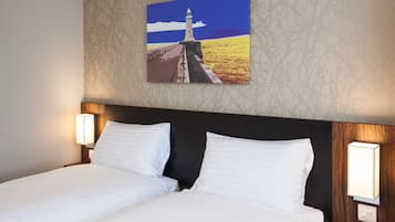 Ett hotellrum med en säng, två sänglampor och en tavla som föreställer en fyr, upphängd på väggen.