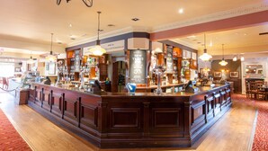 Eine Bar mit einer Holztresen, mehreren hängenden Leuchten und einem roten Teppichboden.