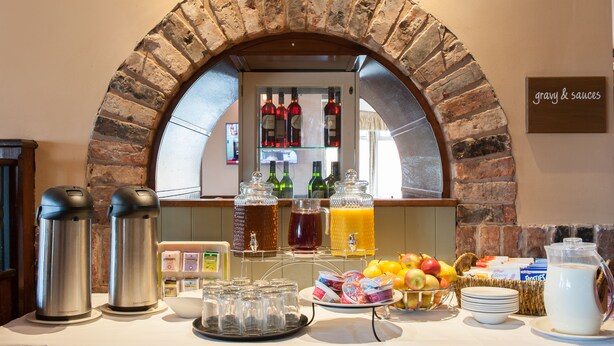 Ein Frühstücksbuffet mit Steingewölbe, verschiedenen Speisen und Getränkespendern.