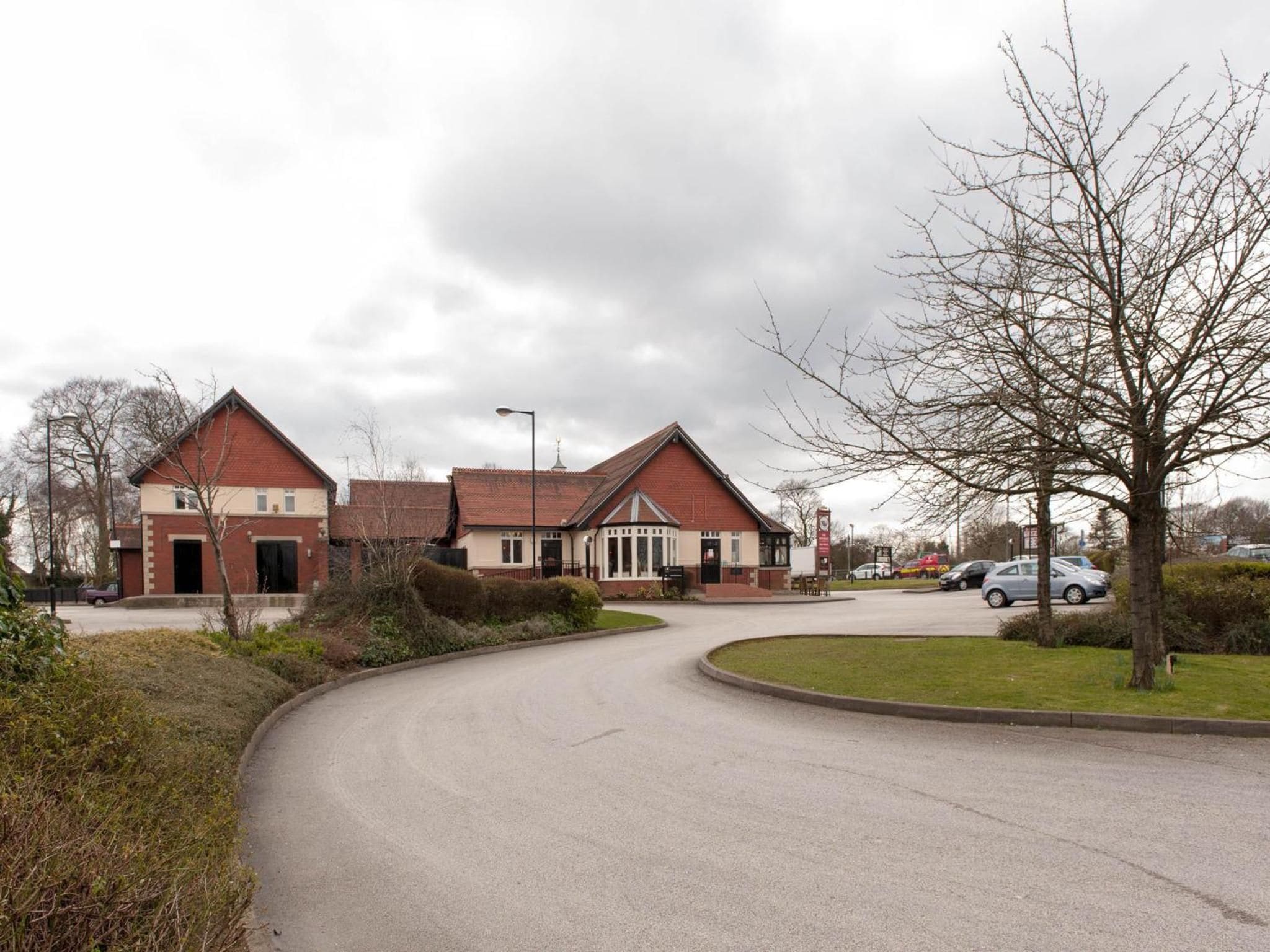 A residential area with a curved road leading to a row of houses with red roofs and white trim.