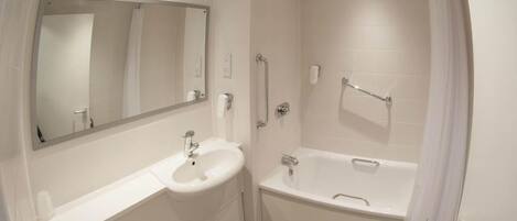 A modern bathroom with a sink, mirror, and bathtub.