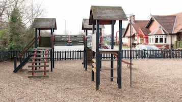 A playground with wooden structures and a fenced area.