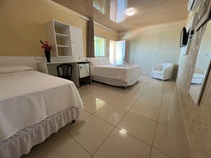 Een hotelkamer met twee bedden, een bureau, een stoel, een televisie en een spiegel.