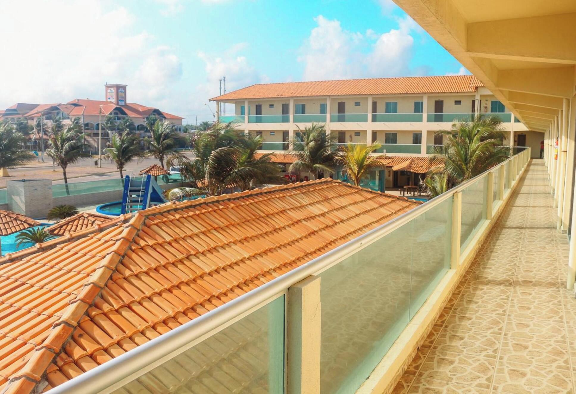 A hotel balcony with a view of a swimming pool and palm trees.