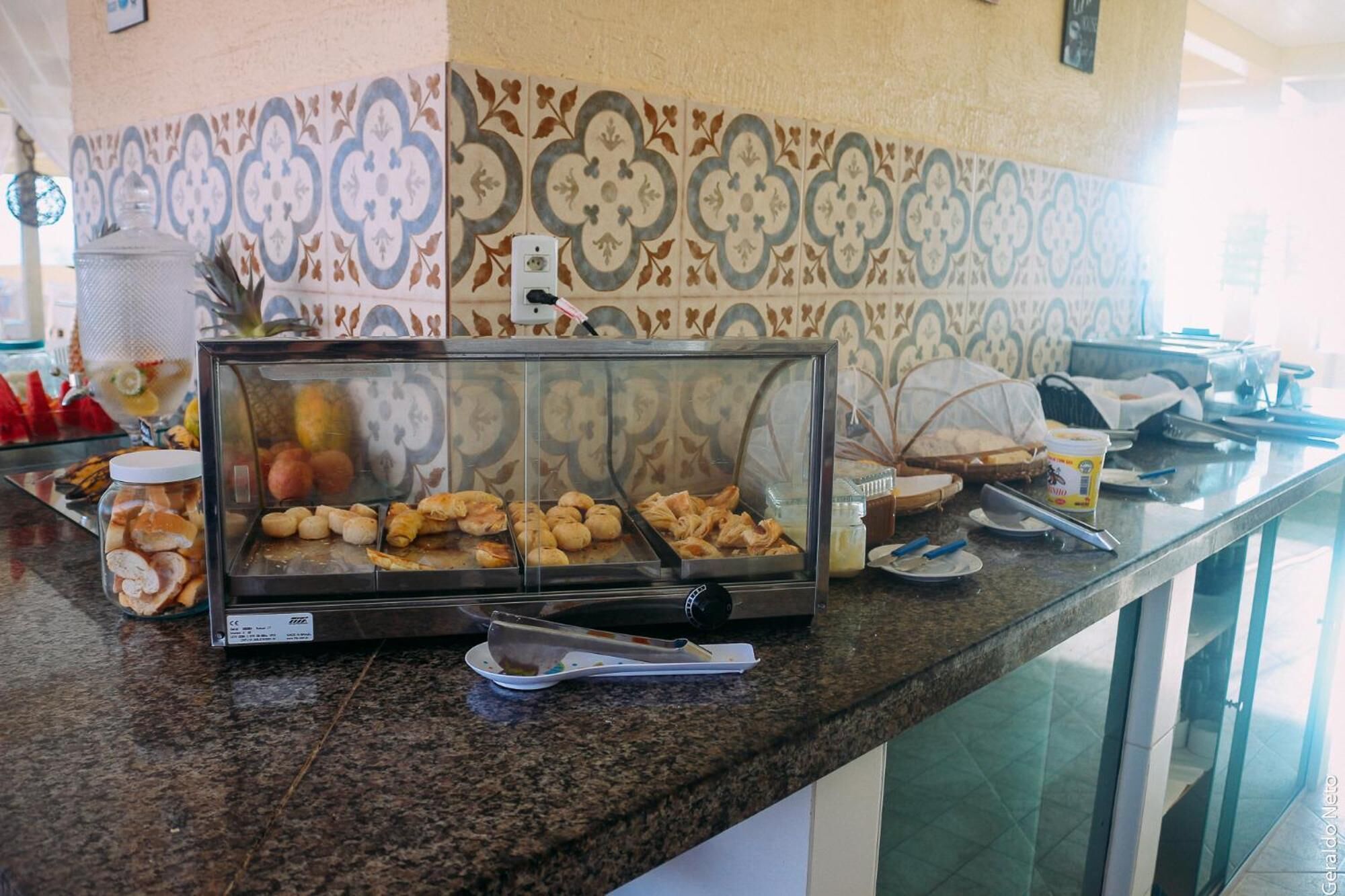 Un mostrador de buffet con una vitrina de cristal que contiene pasteles y una estación de café.