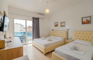Quarto de hotel com duas camas, uma escrivaninha e varanda com vista para edifícios.