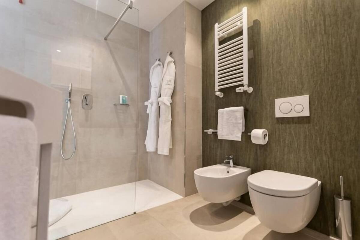 A modern bathroom with a glass shower enclosure, a bidet, and a toilet.