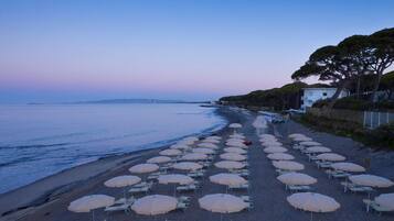 A beach with rows of sunbeds and umbrellas along the shore.