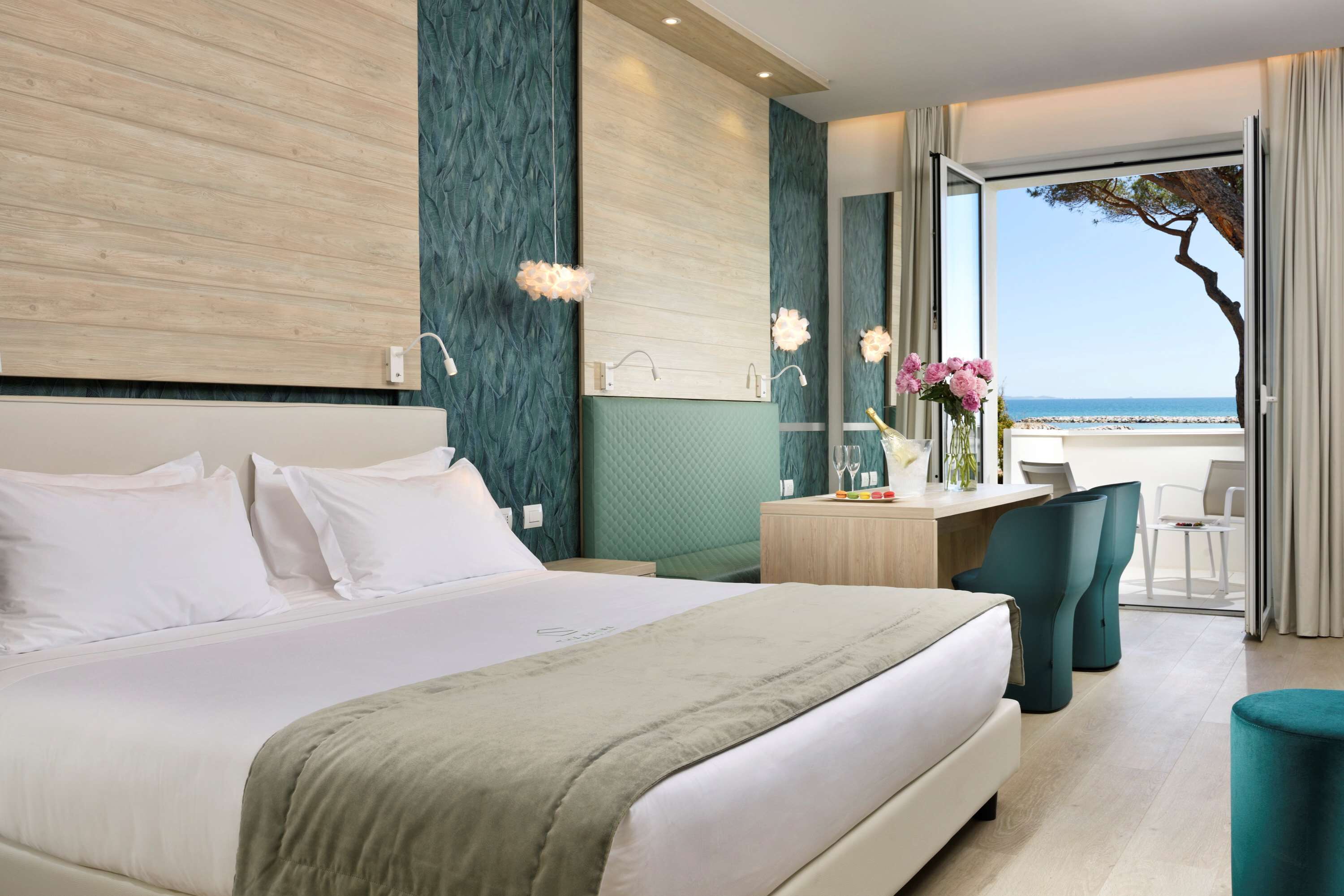 Una habitación de hotel moderna con una cama grande, un escritorio con vistas y un balcón con un árbol.