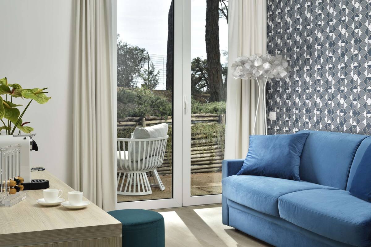 A modern living room with a blue sofa, a coffee machine, and a dining table with cups.